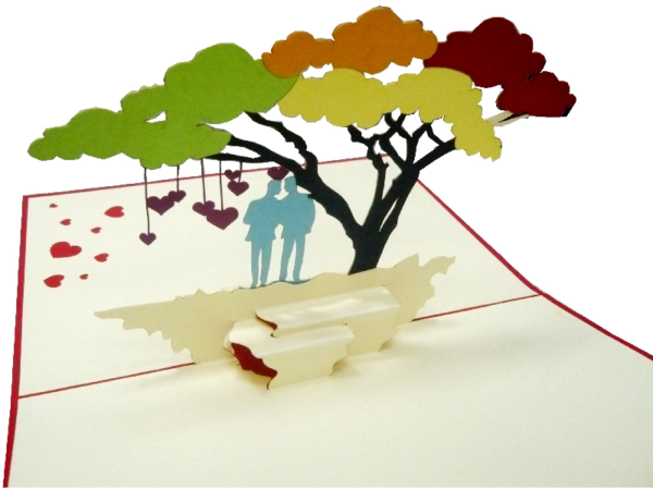 Klappkarte: Hochzeit - Mr. & Mr. Eine Klappkarte aus Papier, die aufgeklappt ist und ein Paar aus zwei Männern in blau unter einem Baum mit herabhängenden Herzen unter bunten Bäumen zu sehen ist.